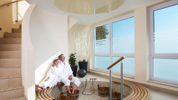 A spa area with a circular seating arrangement, a staircase, and large windows. - Landhotel Weserblick (Beverungen)