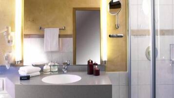 A modern bathroom with a large mirror, two sinks, and a glass shower enclosure.