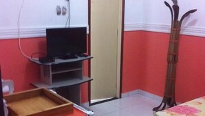 A small room with a bed, a TV on a stand, a wooden chair, and a mirror. - Pousada São Bento II (Sao Bento do Norte)