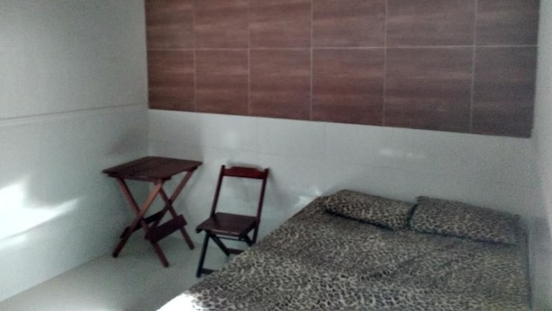 A small room with a bed, a chair, and a small table. - Pousada São Bento II (Sao Bento do Norte)