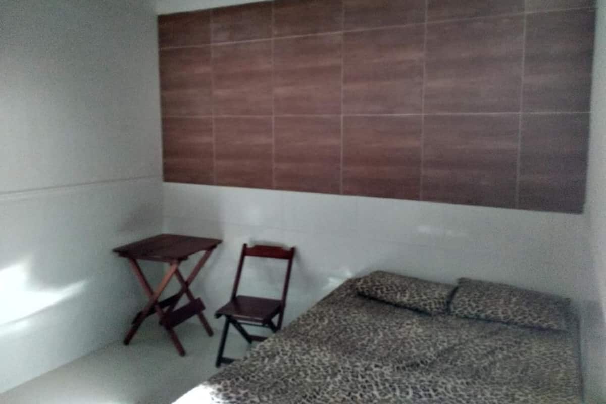 Ein kleines Zimmer mit einem Bett, einem Sessel und einem kleinen Tisch.