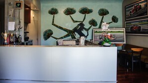 Modernilla designilla sisustettu vastaanottoaula, jossa on suuri abstrakti seinätaideteos, vastaanottotiski ja oleskelualue tuoleineen.