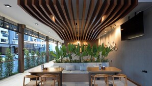 A modern outdoor seating area with wooden furniture, a large plant, and a TV mounted on the wall.