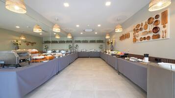 A buffet setup with multiple serving stations, overhead lighting, and wall-mounted kitchen utensils.
