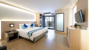 A hotel room with a bed, bedside table, TV, and a balcony with a view.