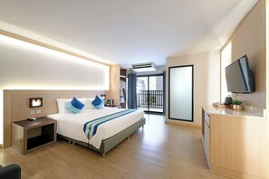 A hotel room with a bed, bedside table, TV, and a balcony with a view.