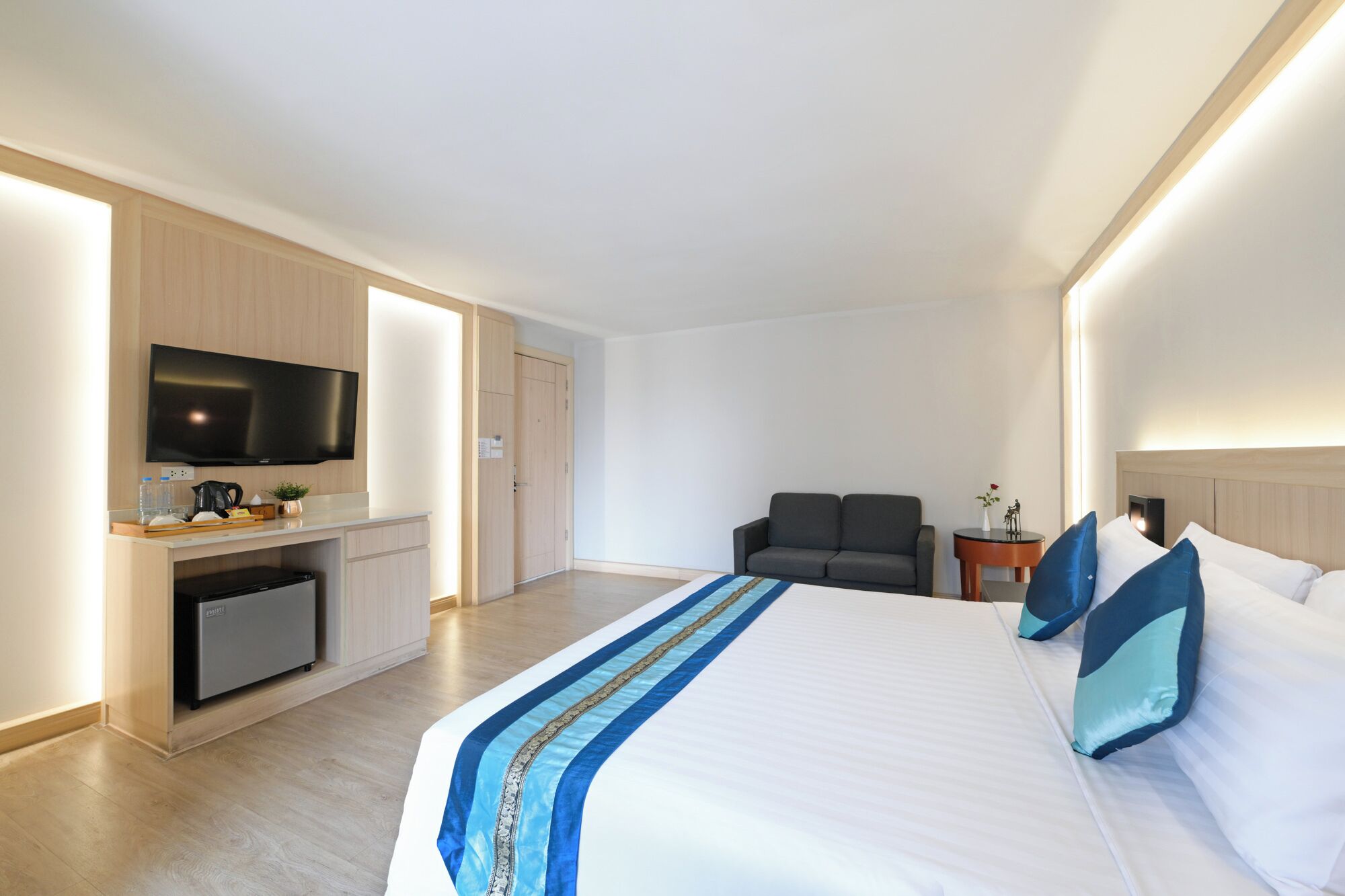 Une chambre d’hôtel comprenant un lit, une télévision, un bureau avec une machine à café, une chaise et une petite table.