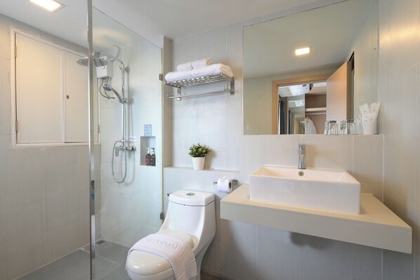 A modern bathroom with a shower, toilet, sink, and a large mirror.