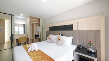 Quarto de hotel com cama, mesa de cabeceira, espelho, guarda-roupa e secretária.