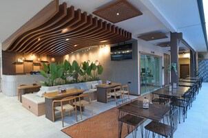 A modern restaurant with a long counter, seating area, and a TV screen.