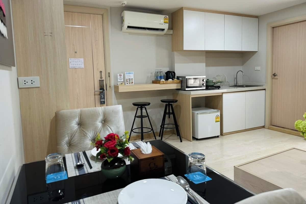 A modern kitchen with a microwave, toaster, and sink. There is a dining area with a table, chairs, and a vase of flowers.