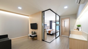 A modern hotel room with a large bed, a TV, a desk, and a bathroom.