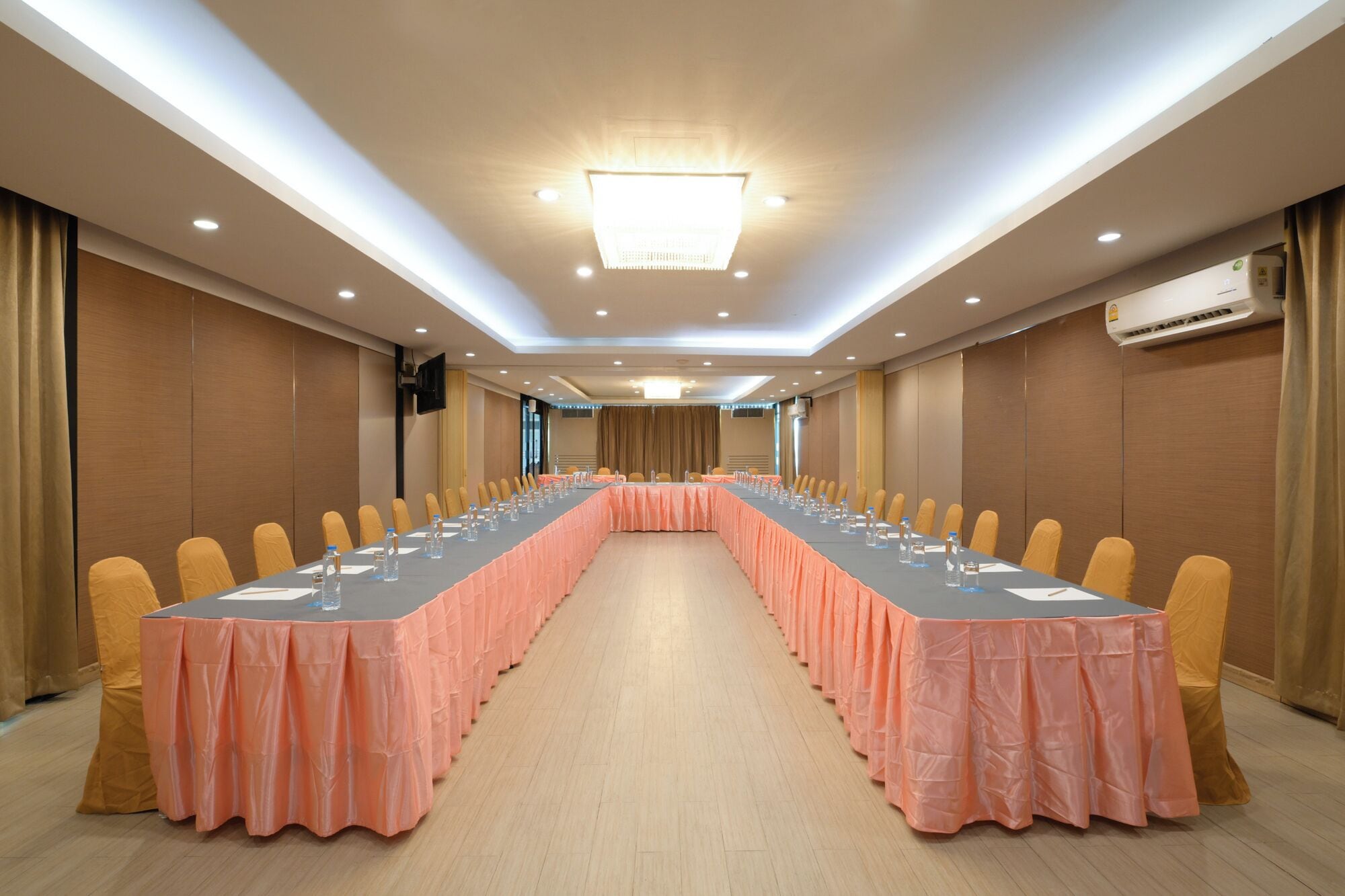 Un salón de conferencias con una mesa larga, sillas y un equipo de aire acondicionado.
