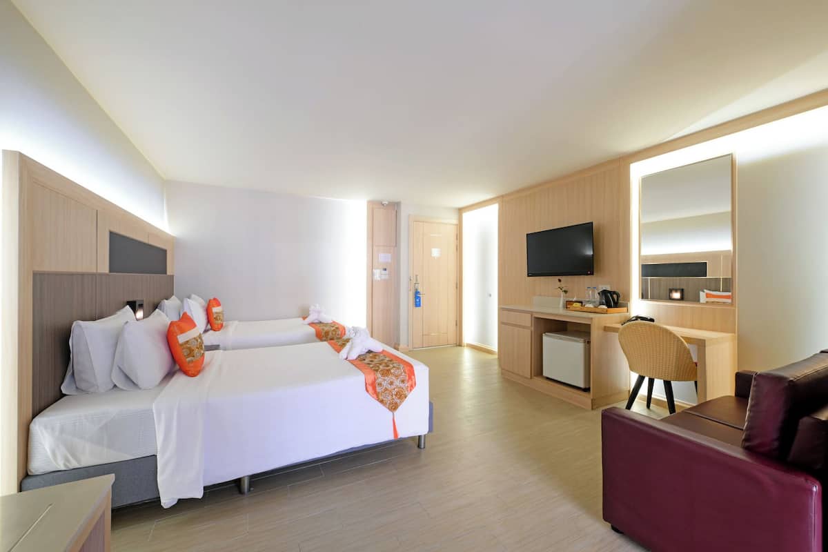 A hotel room with a bed, a desk, a chair, a TV, and a mirror.