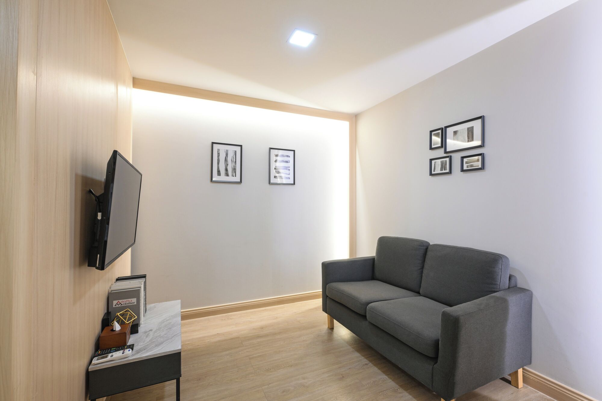 Una sala de estar moderna con un televisor de pantalla plana, un sofá gris y obras de arte enmarcadas en las paredes.