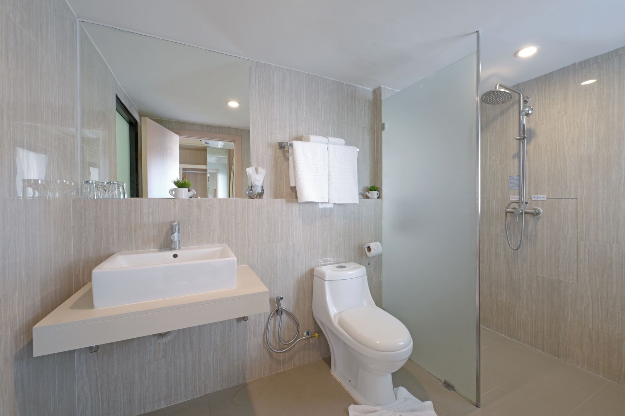 Et moderne badeværelse med vask, toilet og brusebad.