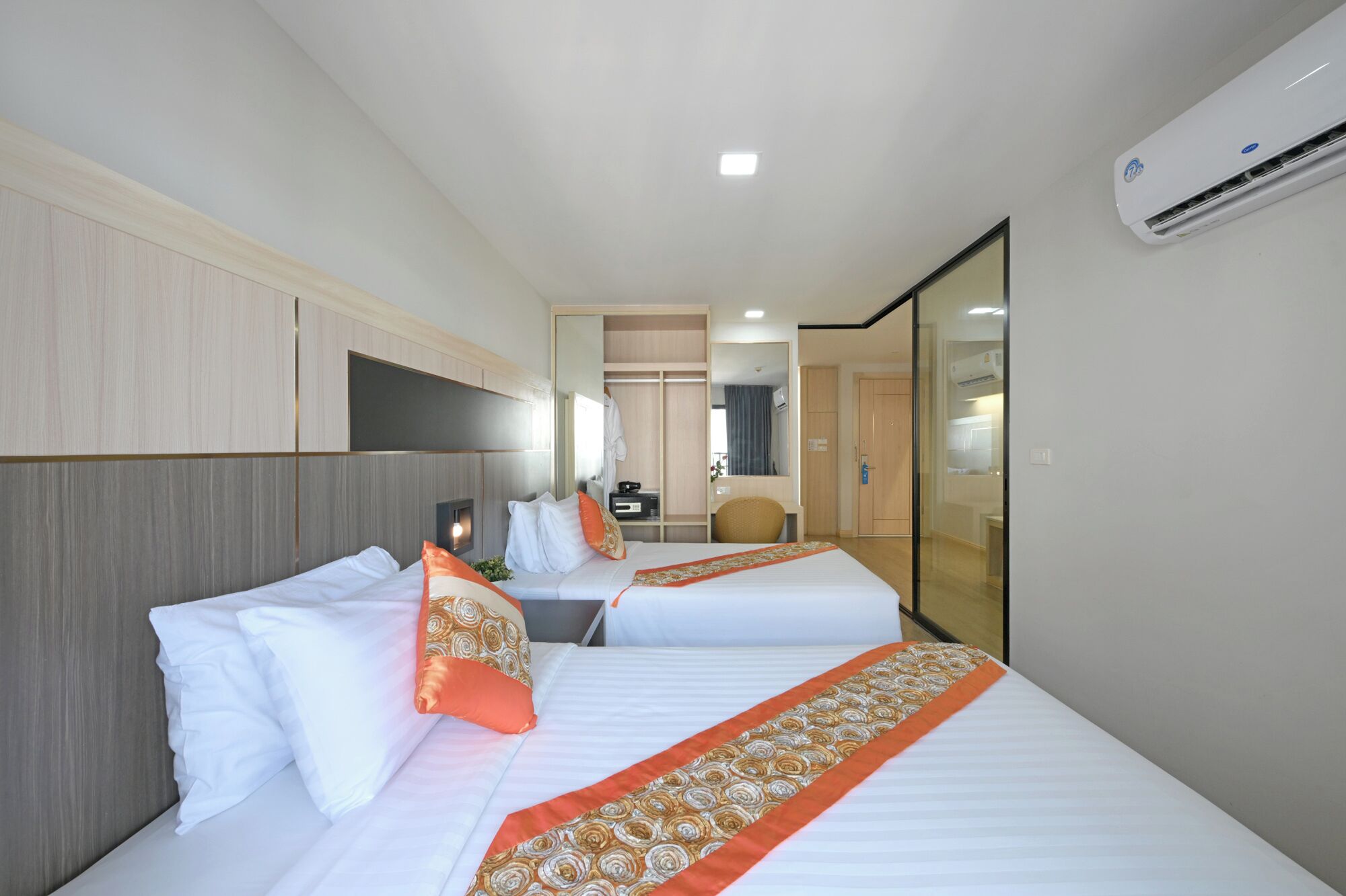Habitación de hotel con dos camas, un escritorio, una silla, un espejo y un equipo de aire acondicionado.