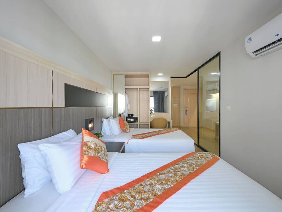 Habitación de hotel con dos camas, un escritorio, una silla, un espejo y un equipo de aire acondicionado.