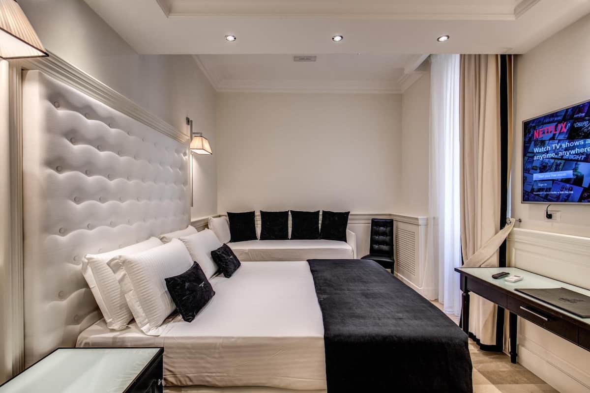 A hotel room with a large bed, a desk, and a TV mounted on the wall.