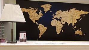 A reception desk with a world map backdrop, a lamp, and a card holder. - Hotel dei Quiriti Suite (Rome)