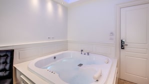 A modern bathroom with a large bathtub, a door, and a lighted ceiling. - Hotel dei Quiriti Suite (Rome)