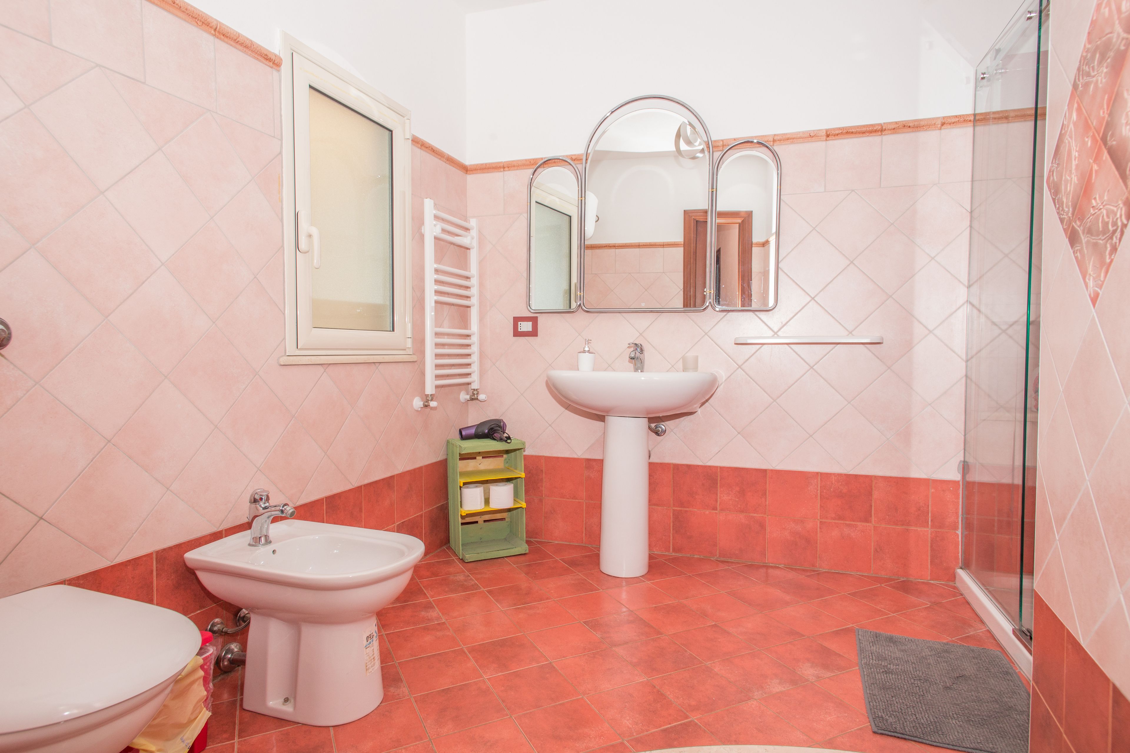 Un baño con inodoro, bidé, lavamanos y cabina de ducha de vidrio.