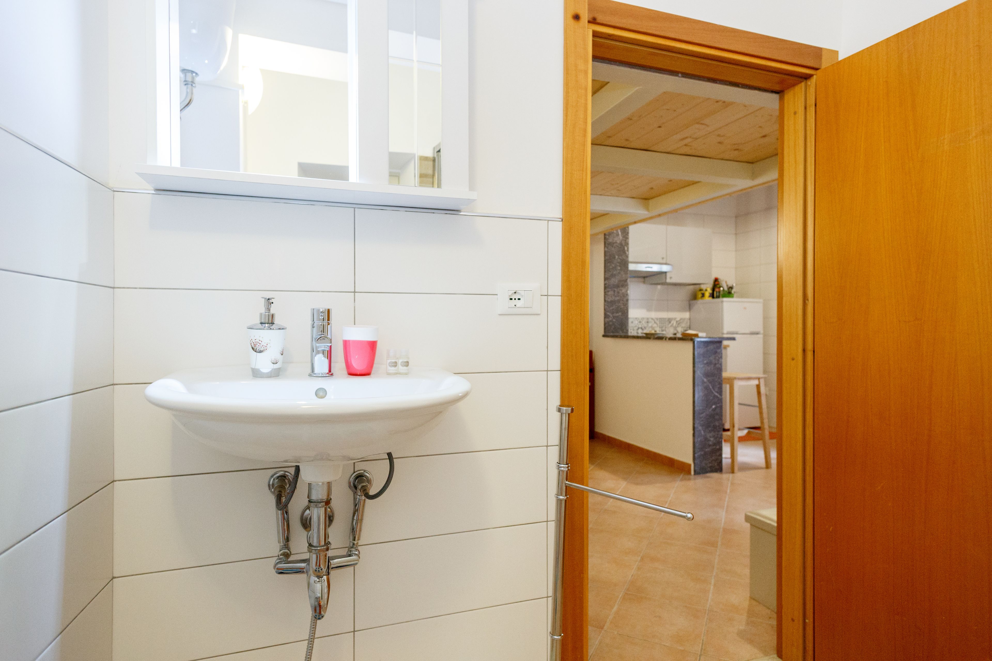 Un baño con un lavamanos blanco, un espejo y una ducha.