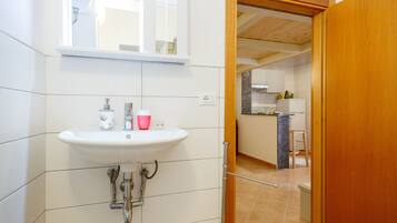 Un baño con un lavamanos blanco, un espejo y una ducha.