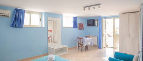Una habitación con cama, una silla azul, una mesa y un armario.