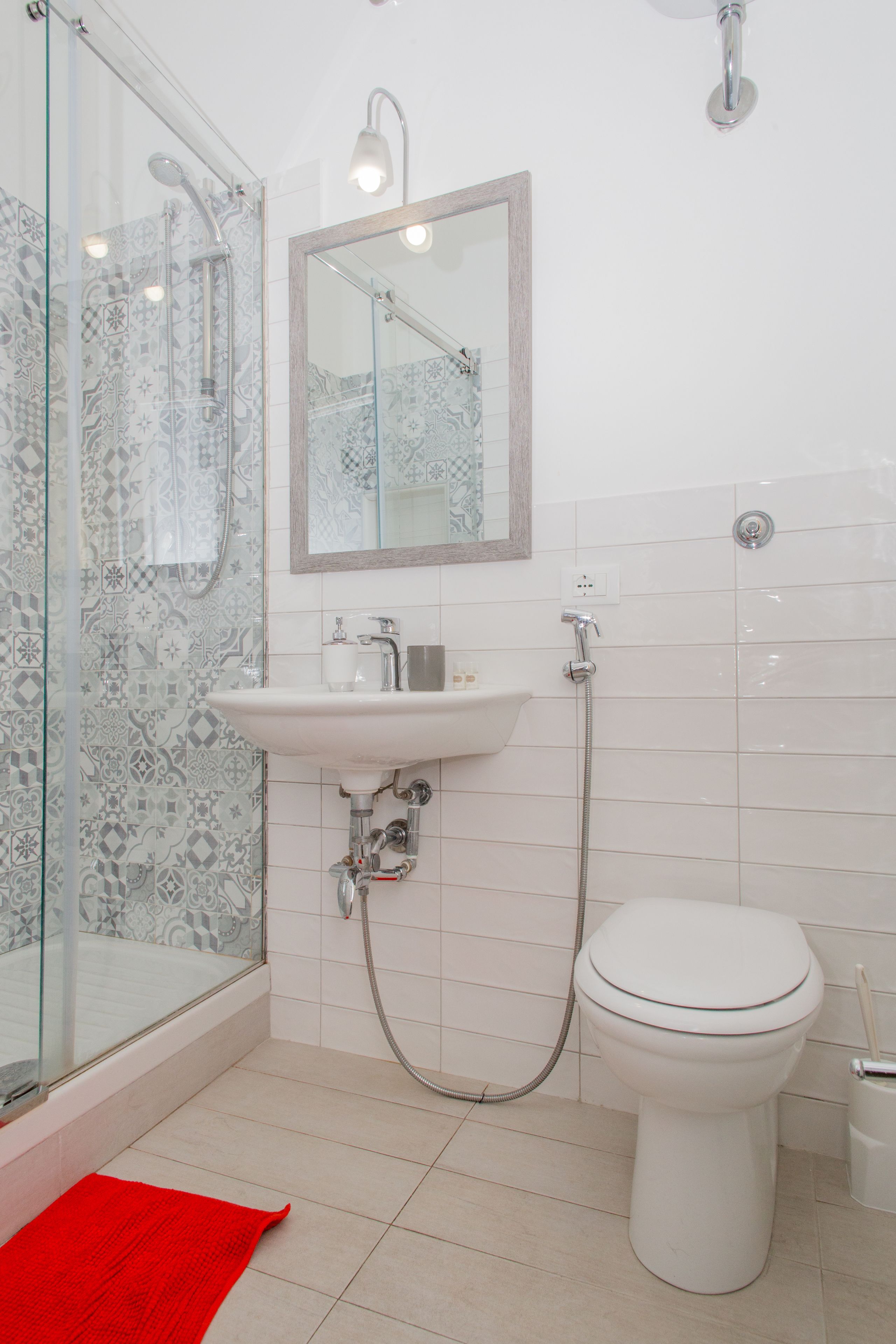 A bathroom with a glass shower enclosure, a sink with a mirror above it, and a toilet.