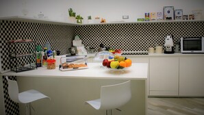 A modern kitchen with a checkered backsplash, white cabinetry, and a fruit bowl on the counter. - Hermes Rooms for tourists (Naples)