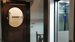 A hotel entrance with a wooden door, a small outdoor area with a metal gate, and an elevator. - Hermes Rooms for tourists (Naples)