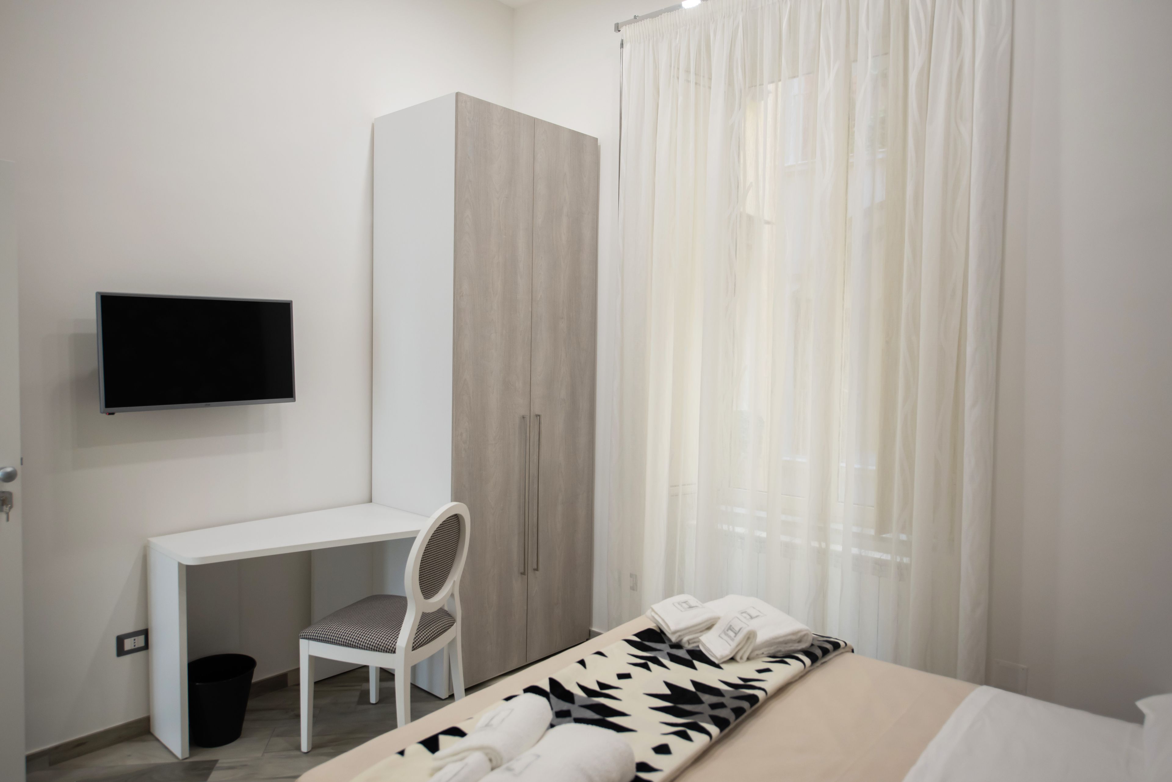 Une chambre à coucher avec un lit, un bureau, une chaise, une armoire et un téléviseur.