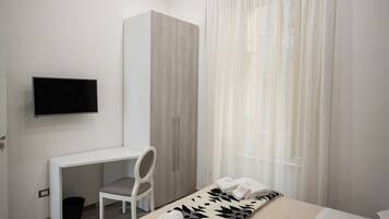Une chambre à coucher avec un lit, un bureau, une chaise, une armoire et un téléviseur.