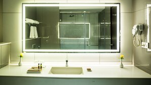 Un baño moderno con un espejo grande, un lavabo y dos jarrones con flores.