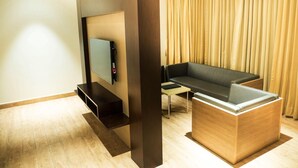Una sala de estar moderna con un televisor de pantalla plana montado en un panel de madera, un sofá gris y una mesa de centro de madera.