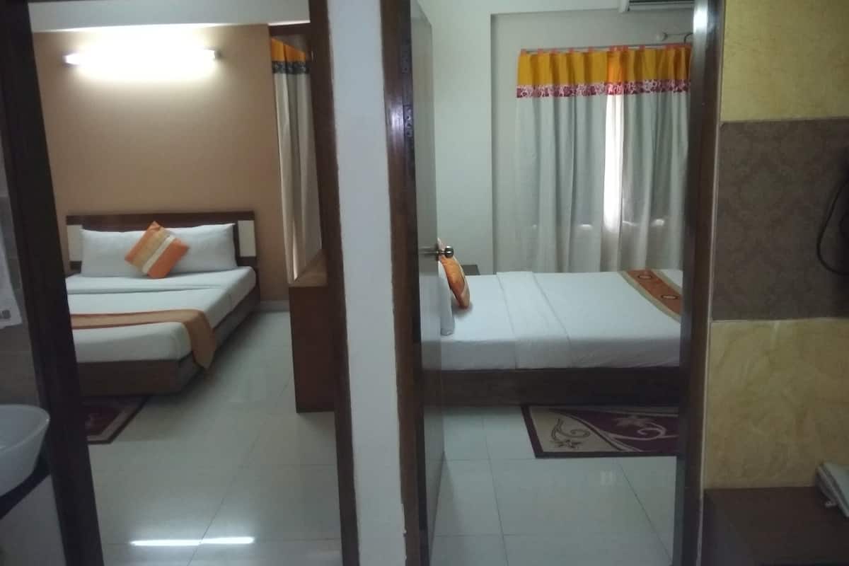 A hotel room with a bed, a bedside table, a mirror, and a window with curtains.