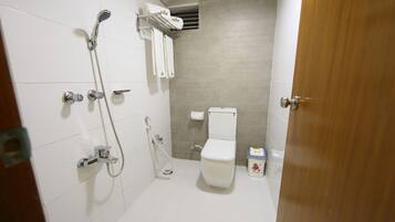 A small, modern bathroom with a toilet, shower, and a towel rack.