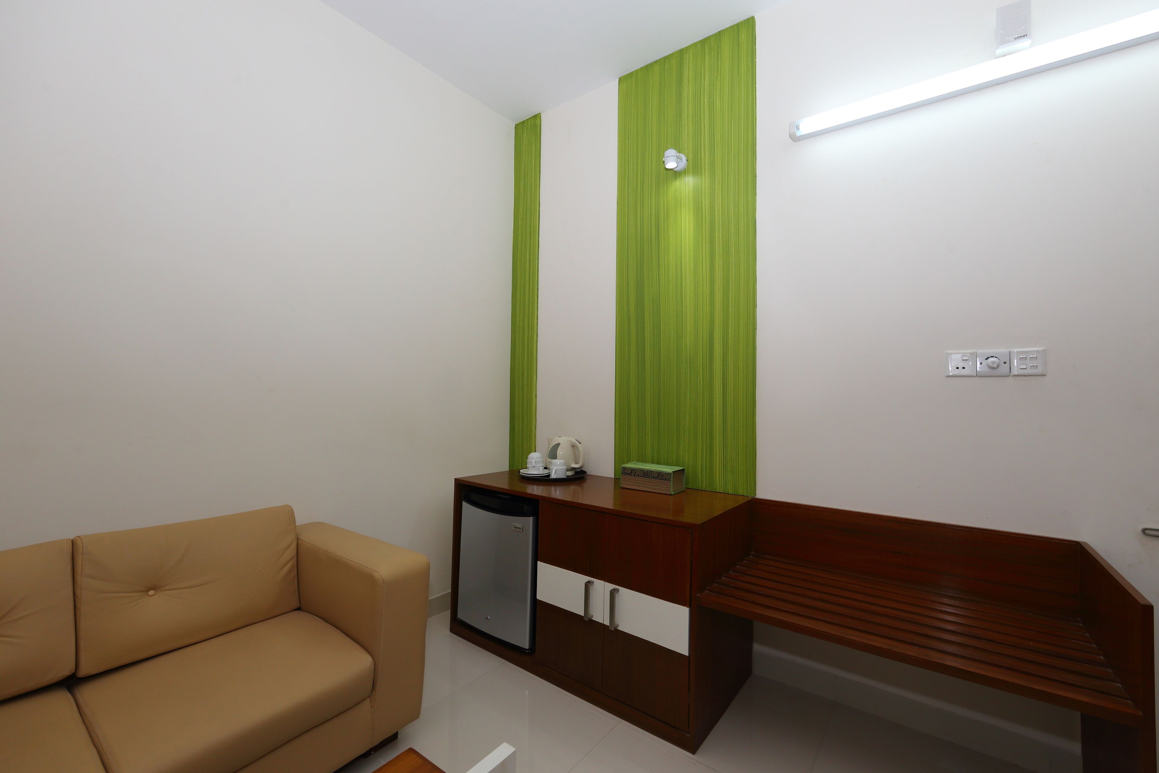 A room with a brown sofa, a wooden desk, and a green accent wall.