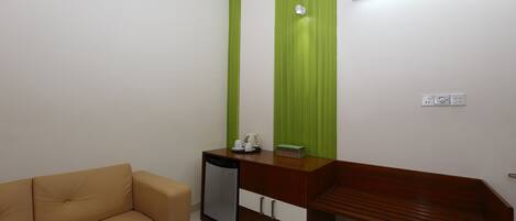 A room with a brown sofa, a wooden desk, and a green accent wall.
