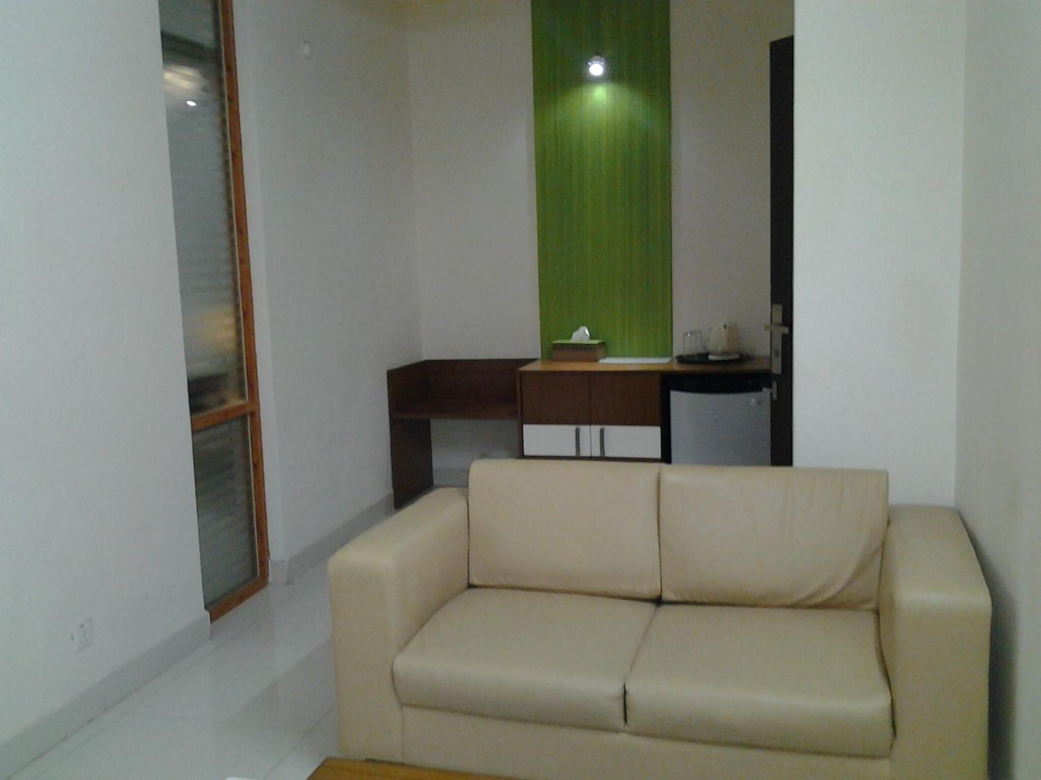 A living room with a beige sofa, a small wooden table, and a green curtain.