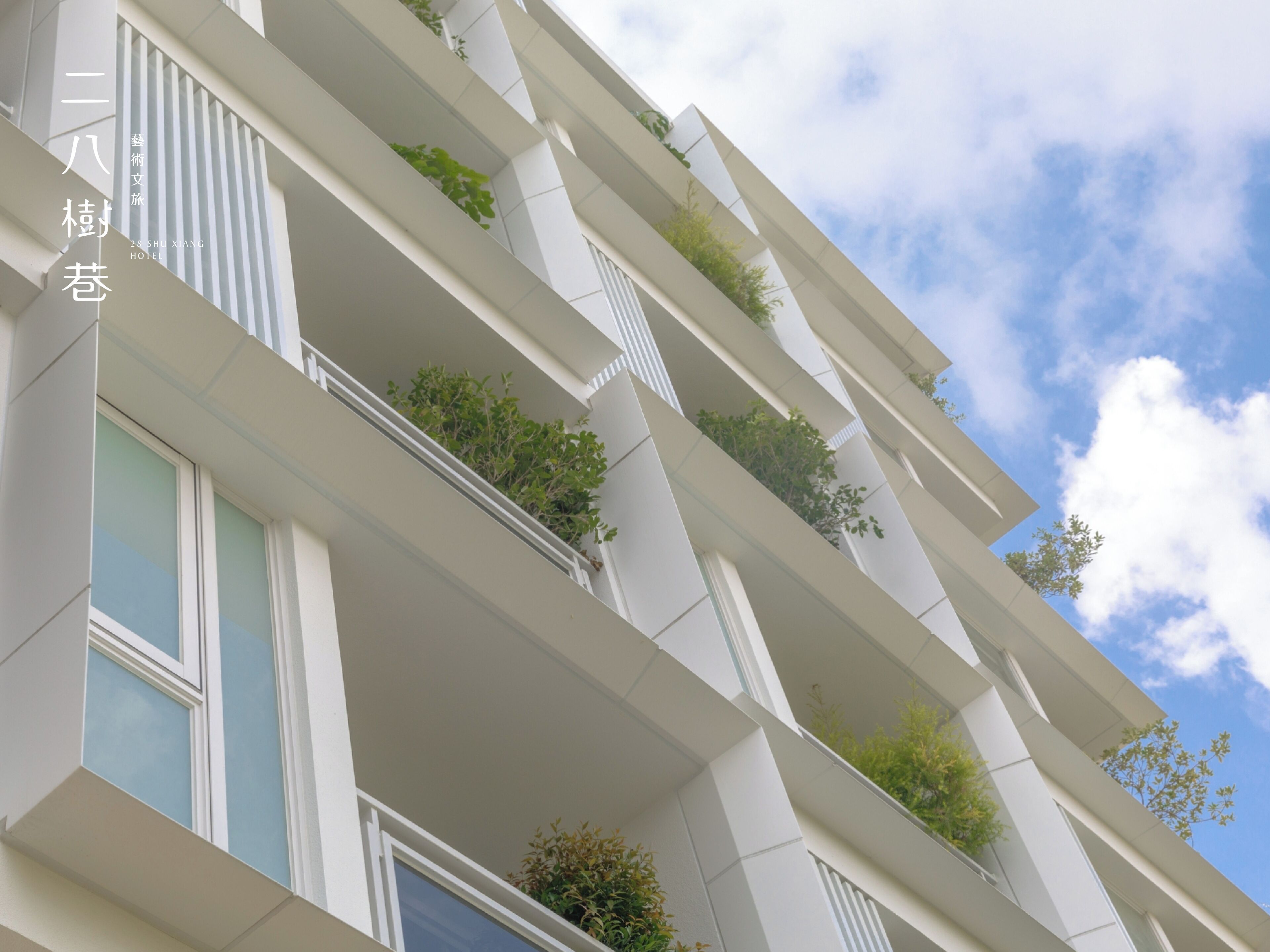 A modern hotel building with multiple balconies, large windows, and a clear sky.