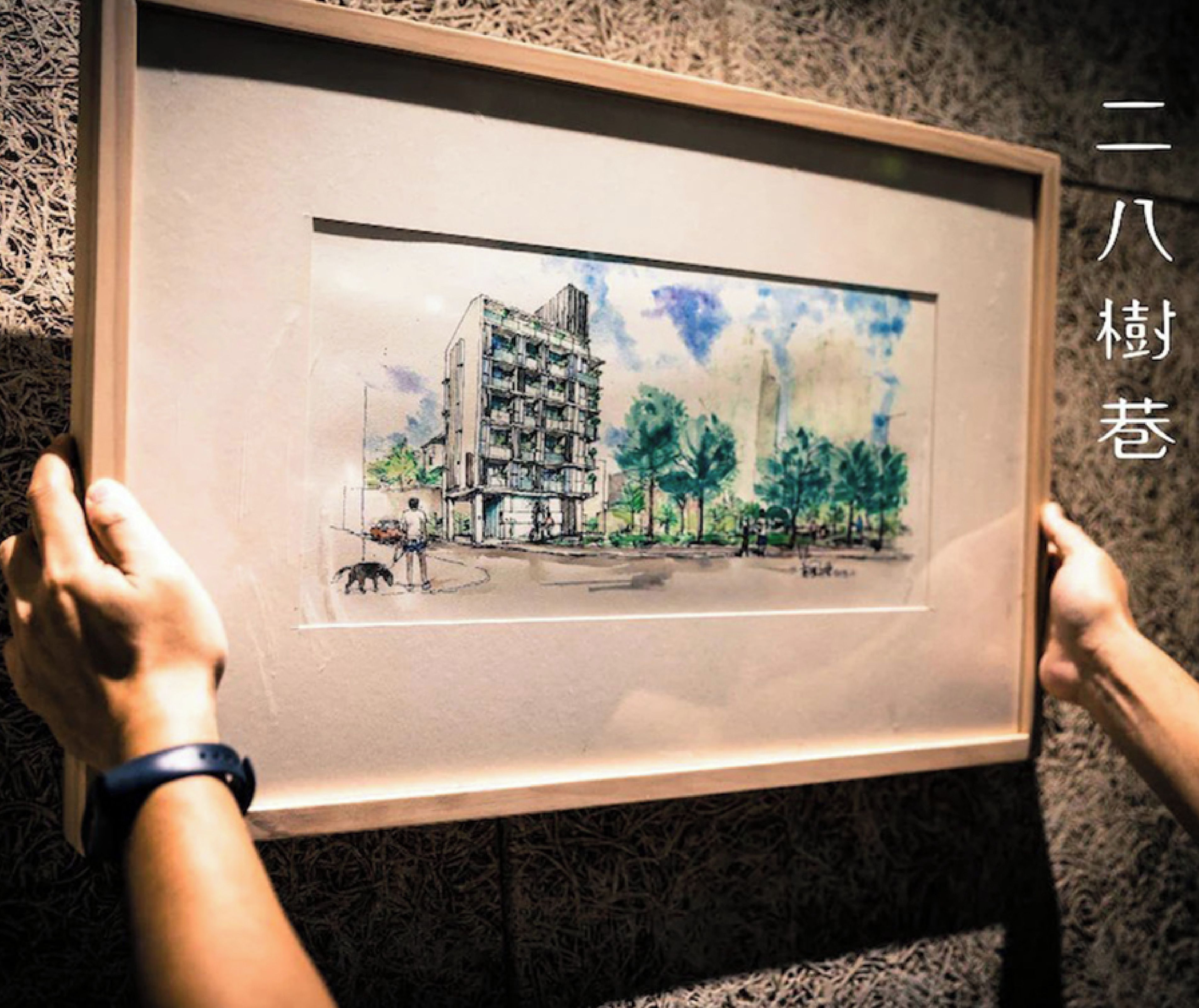 A framed architectural drawing of a building with multiple floors and balconies, held by two hands.
