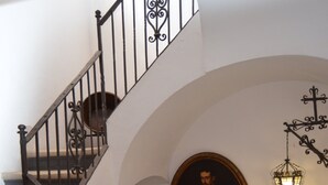 A staircase with ornate metal railings, a round portrait, and a wall-mounted lantern. - In the center, apartment in manor house. (Sanlúcar de Barrameda)