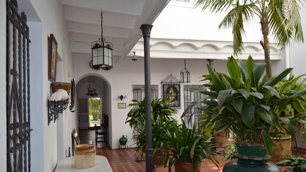 A covered courtyard with a tiled floor, potted plants, and hanging lanterns. - In the center, apartment in manor house. (Sanlúcar de Barrameda)