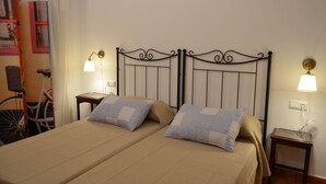 A double bed with a metal headboard, two bedside tables with lamps, and a bicycle in the background. - In the center, apartment in manor house. (Sanlúcar de Barrameda)