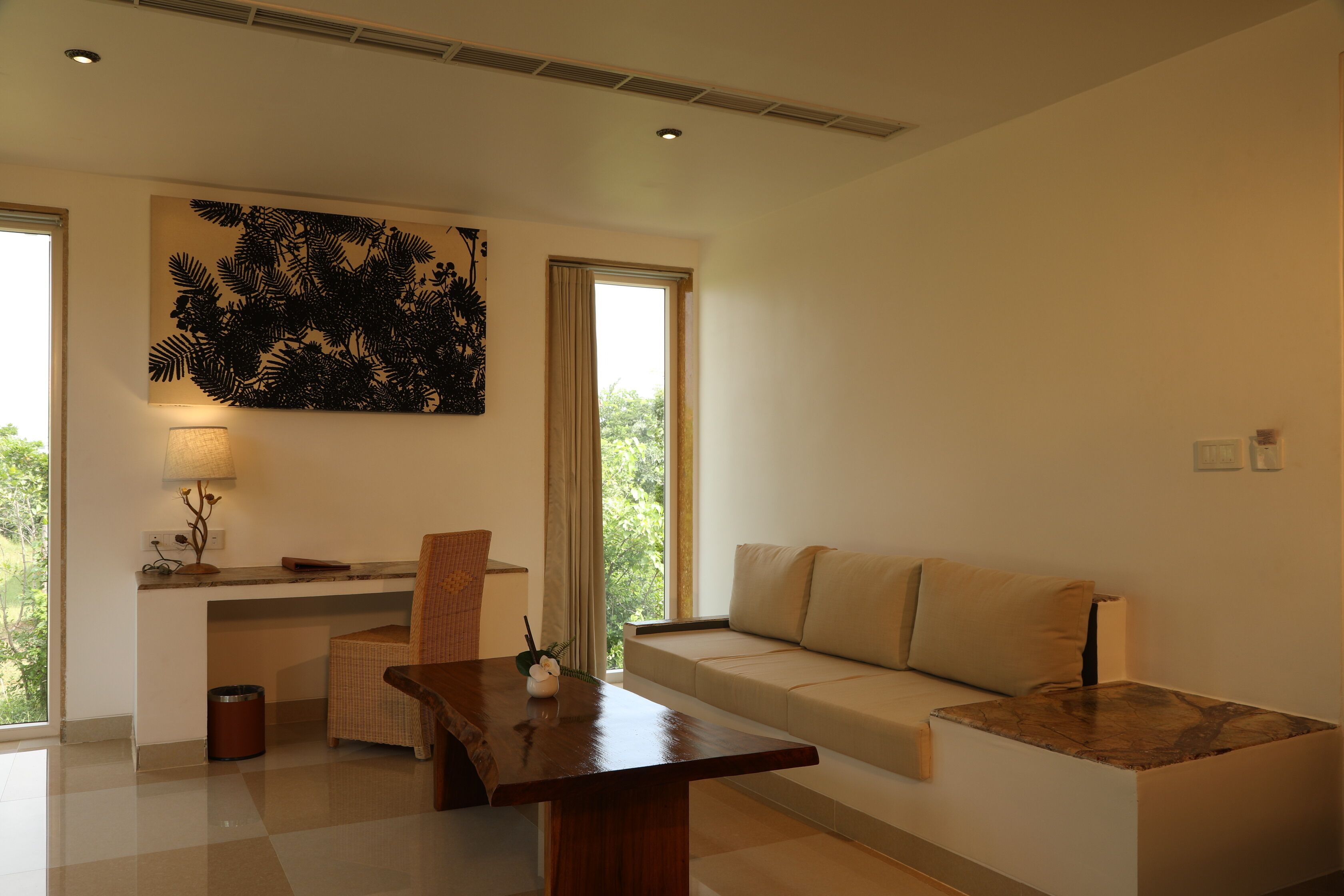 A modern living room with a sofa, a wooden coffee table, a chair, a lamp, and a large wall art piece.