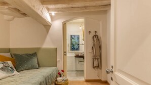 A bedroom with a bed, a small table with a vase and a cup, a door leading to a bathroom, and a coat rack. - Apartments Florence San Lorenzo Terrace (Firenze)