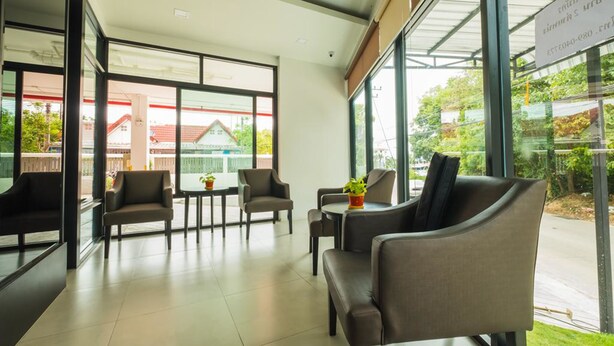 A modern indoor space with glass walls, leather seating, and a view of a residential area. - Innara Hotel (Pattaya)