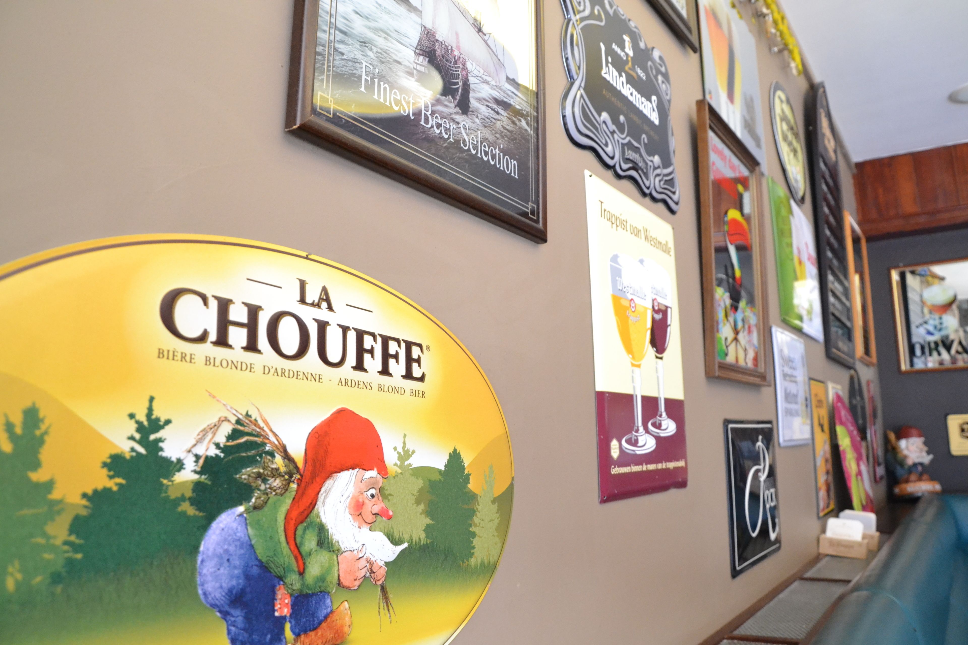 A wall with various framed items, including a prominent sign for 'La Chouffe' beer.